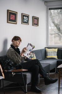 En kvinna som sitter i en soffa i väntrummet och läser en tidning.