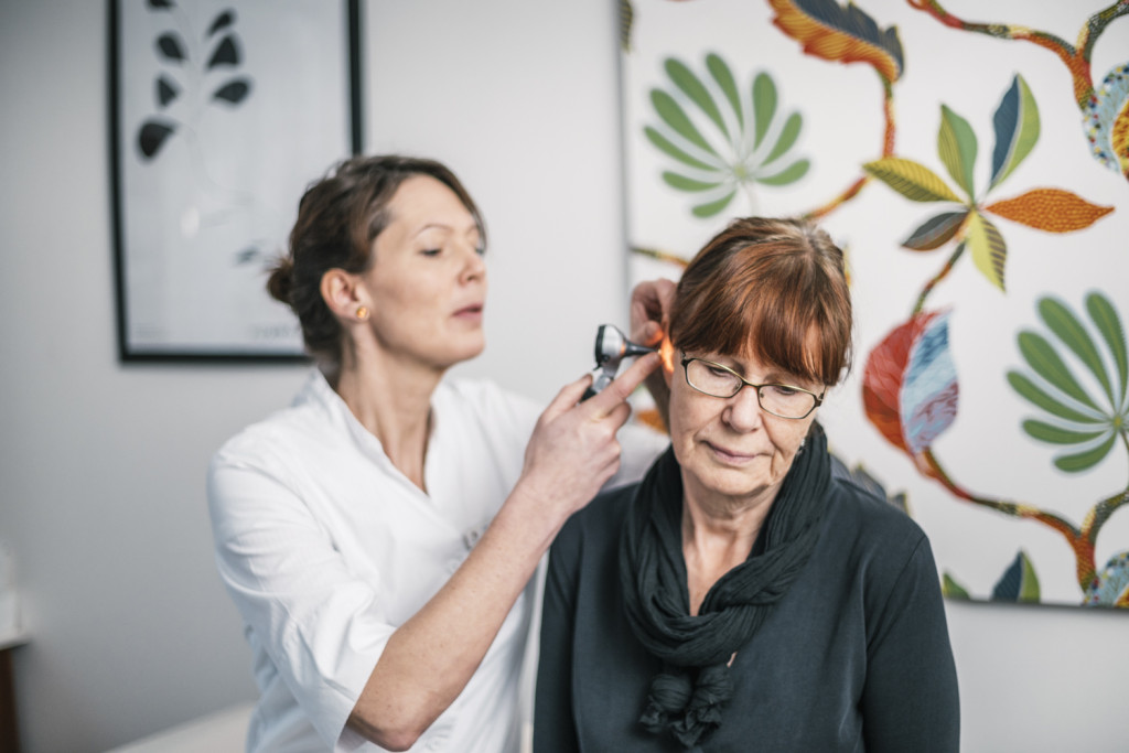 En kvinna får sitt öra undersökt av läkare